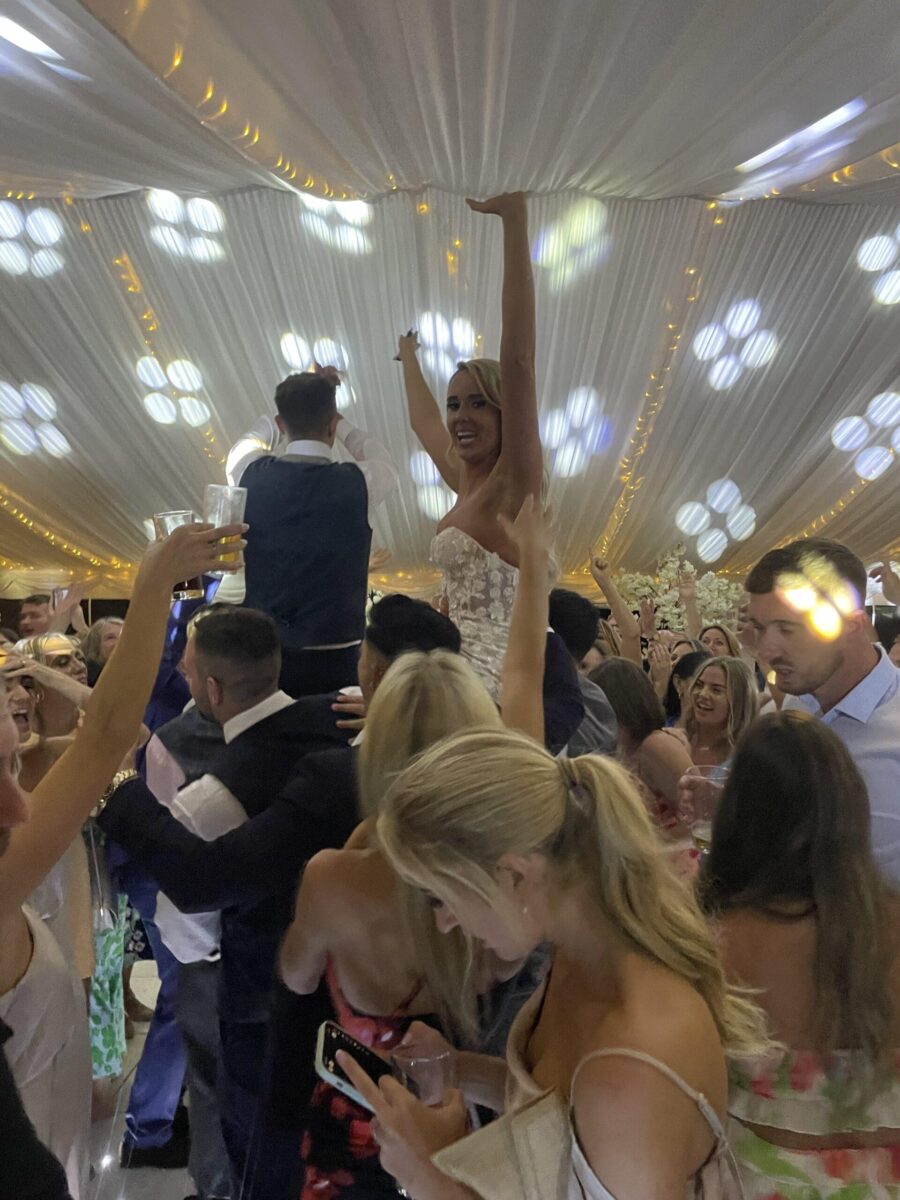 bride lifted up by guests on the dancefloor