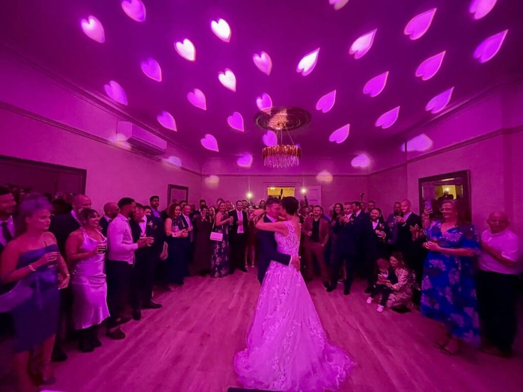 Couple sharing a joyful first dance moment Dancefloor lighting inside an Essex country house venue
